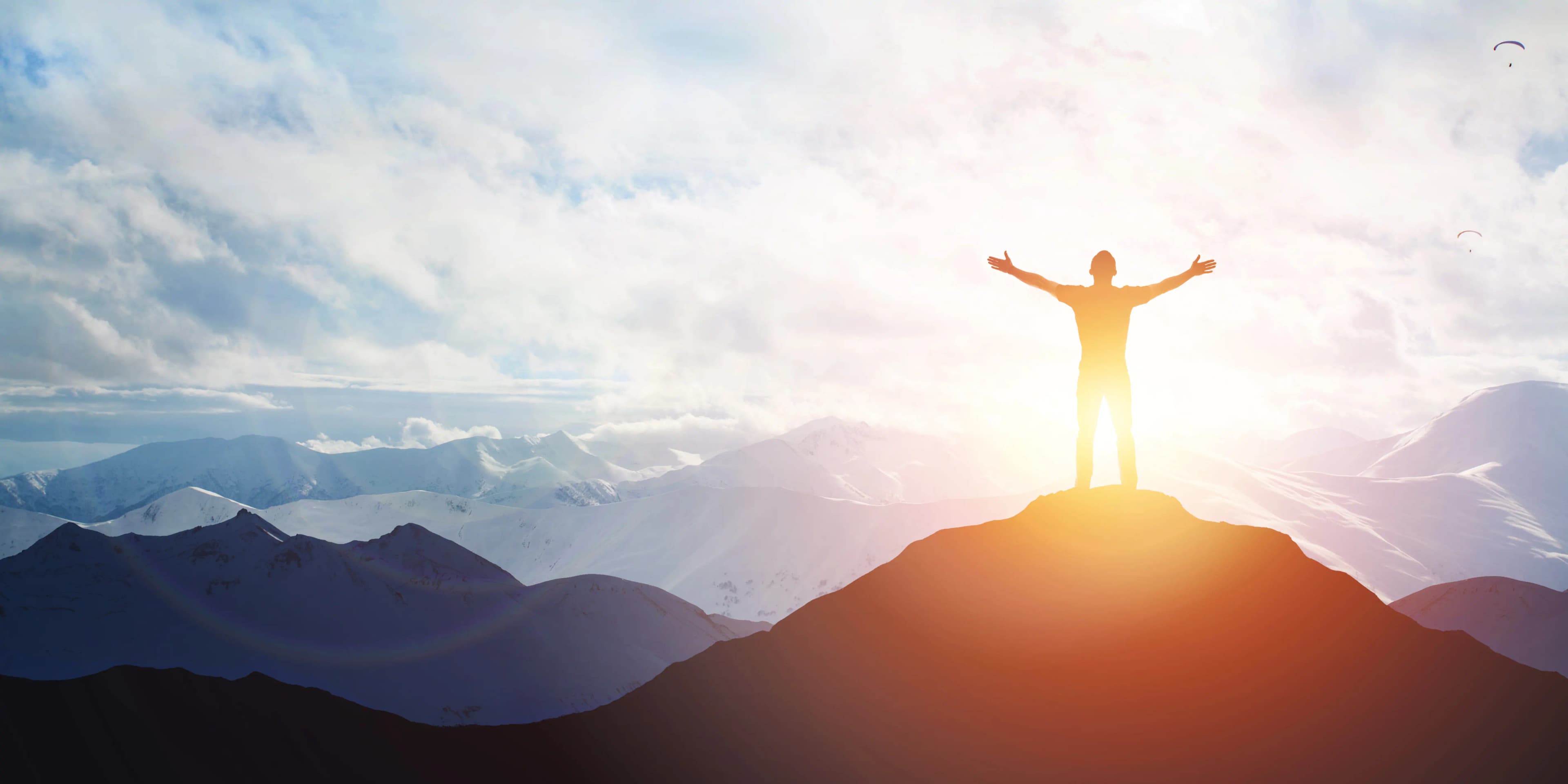 sunrise in the mountains with a person on a peak